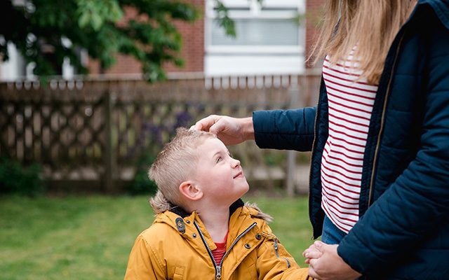 foster child holds hand of foster carer in garden