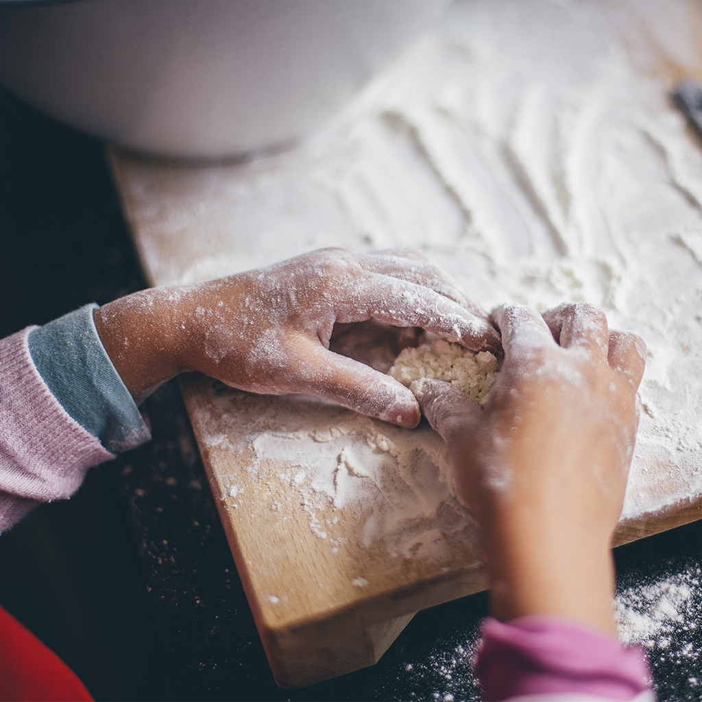 little girl making dough with flour
